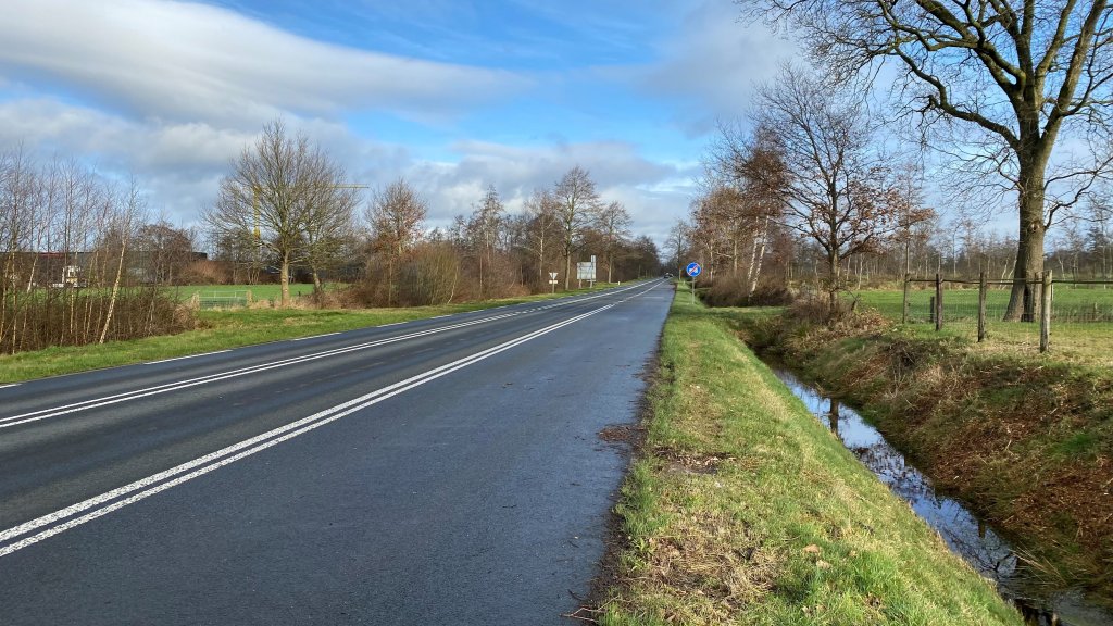 De Uterwei. Een weg met dubbele witte streep tussen bermen met bomen langs de kant.